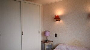 A bedroom with a bed, a nightstand, a lamp, and a wardrobe. - Comfortable 2-room apartment - 4 people - Garden in Font-Romeu (Font-Romeu-Odeillo-Via)