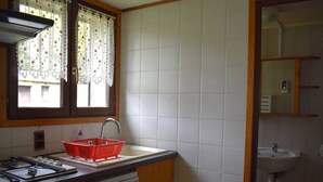 A kitchen with a gas stove, a sink, and a dish drying rack. - Comfortable 2-room apartment - 4 people - Garden in Font-Romeu (Font-Romeu-Odeillo-Via)