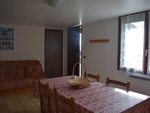 A dining area with a table set for four, a wicker basket on the table, and a patterned tablecloth. - Comfortable 2-room apartment - 4 people - Garden in Font-Romeu (Font-Romeu-Odeillo-Via)