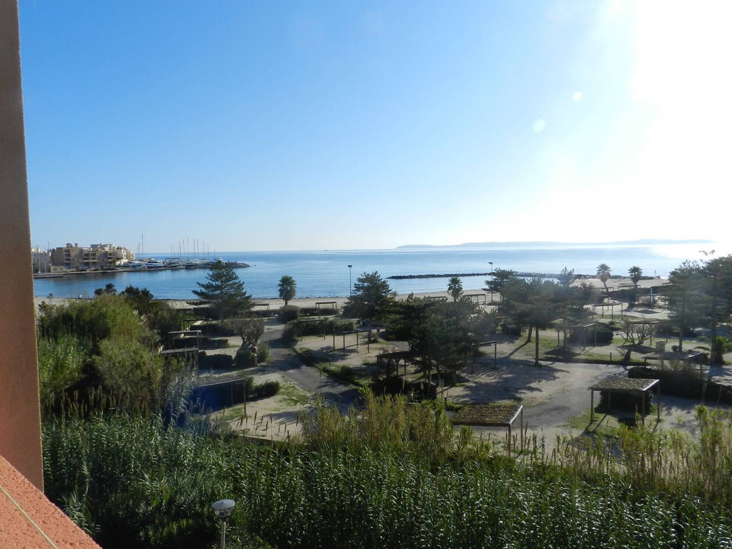 A coastal view with a marina, beach, and greenery.