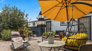 An outdoor patio area with a hanging chair, a yellow umbrella, and a swing chair. - Quiet Guest Suite w/ Private Entry + Garden in Central LA (Los Angeles)