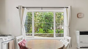 A kitchen with a window, white stove, and a round table with chairs. - Quiet Guest Suite w/ Private Entry + Garden in Central LA (Los Angeles)
