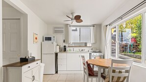 A modern kitchen with white cabinets, a wooden dining table, and a ceiling fan. - Quiet Guest Suite w/ Private Entry + Garden in Central LA (Los Angeles)