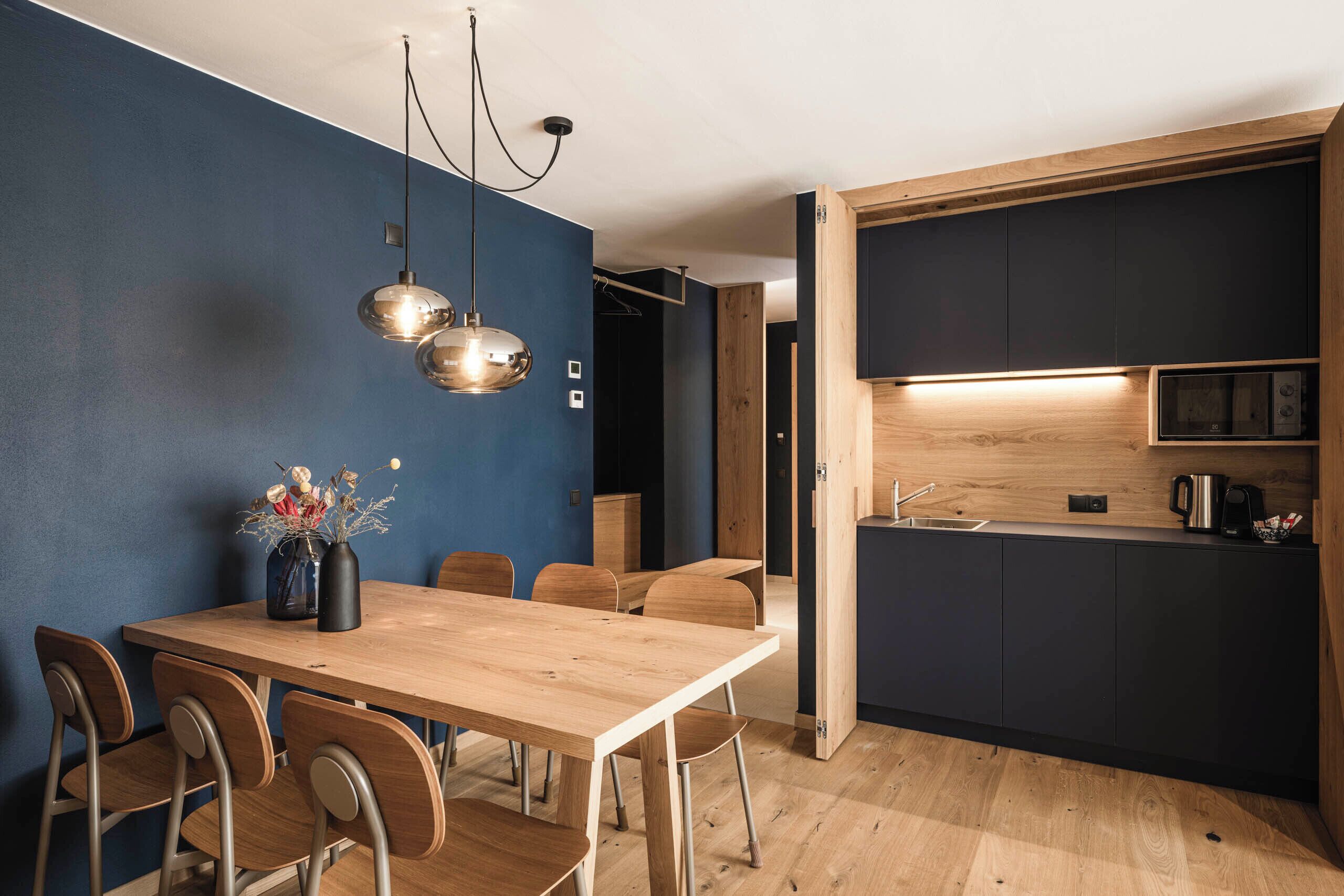 A modern kitchen with dark cabinetry, a wooden countertop, and a built-in oven.