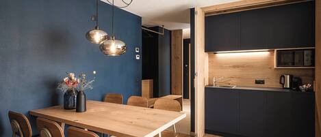 A modern kitchen with dark cabinetry, a wooden countertop, and a built-in oven.