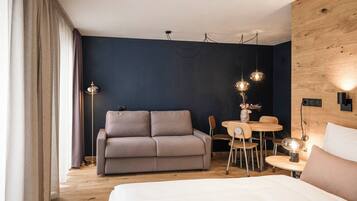 A modern hotel room with a sofa, a small dining table, and a bed.