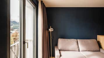 A bedroom with a bed, a floor lamp, and a view of the outdoors.