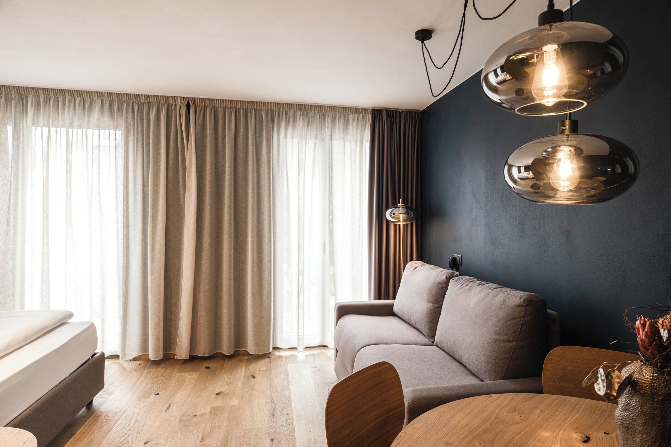 A modern living room with a sofa, a round wooden table, and a lamp.