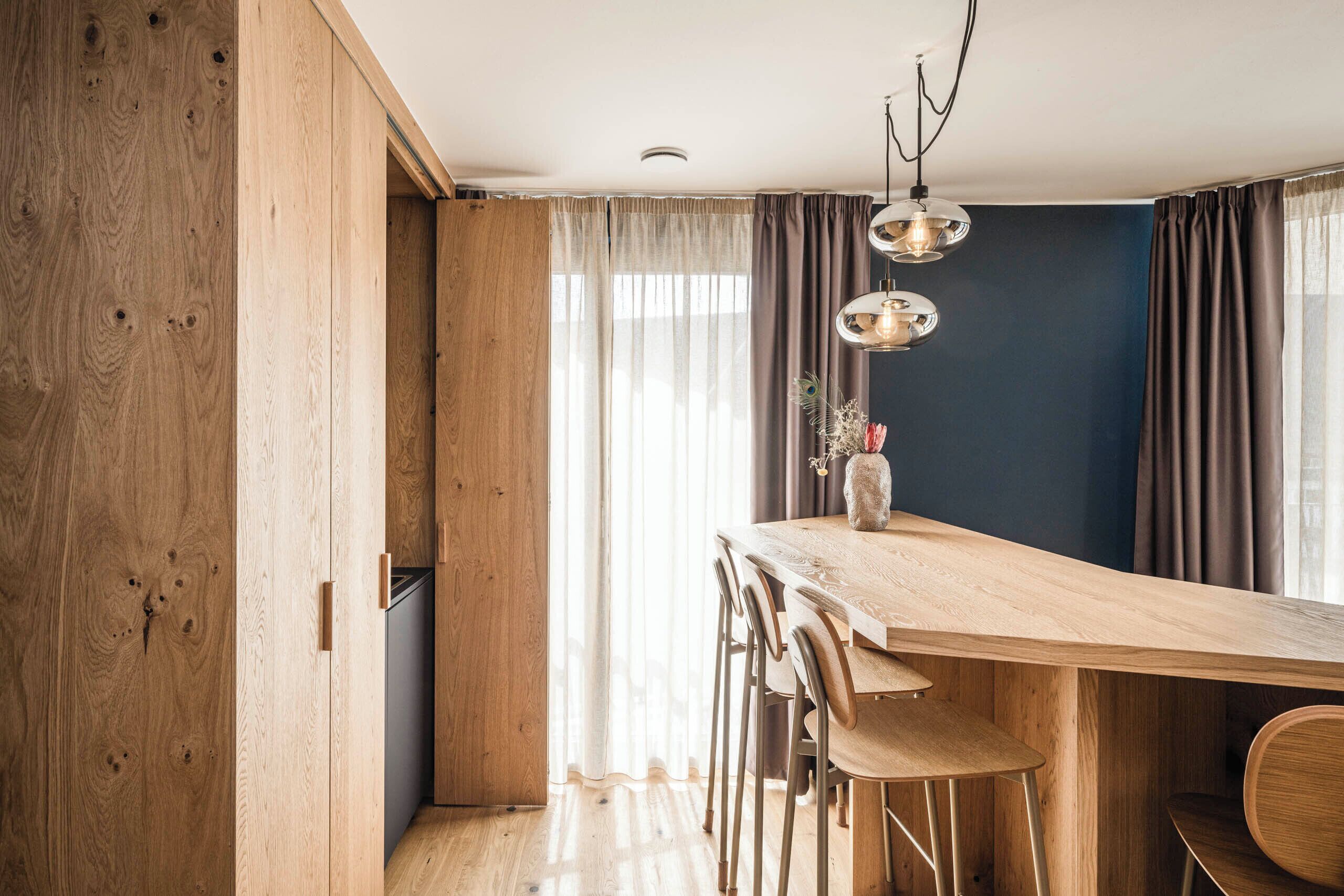 Una cocina moderna con armarios de madera, una amplia mesa de comedor e iluminación colgante.