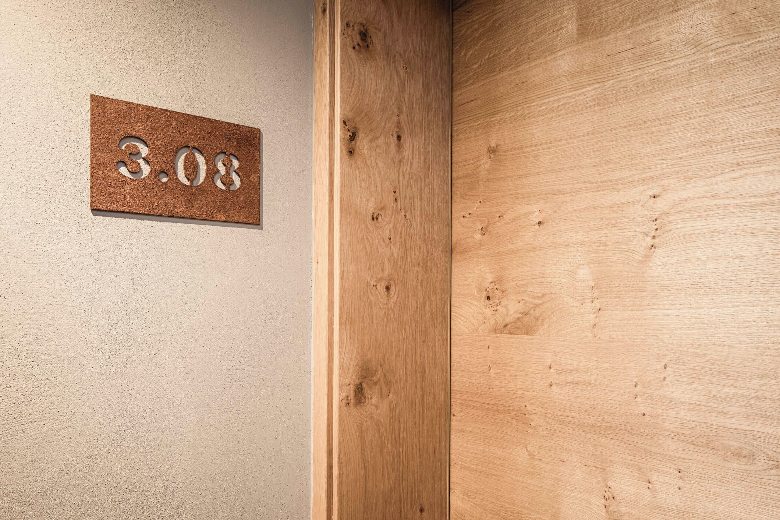 Una porta di legno con un cartello di sughero con il numero '3.08'.