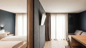 Una habitación de hotel moderna con una cama, un escritorio y una silla. Hay cortinas en las ventanas y un espejo montado en la pared.
