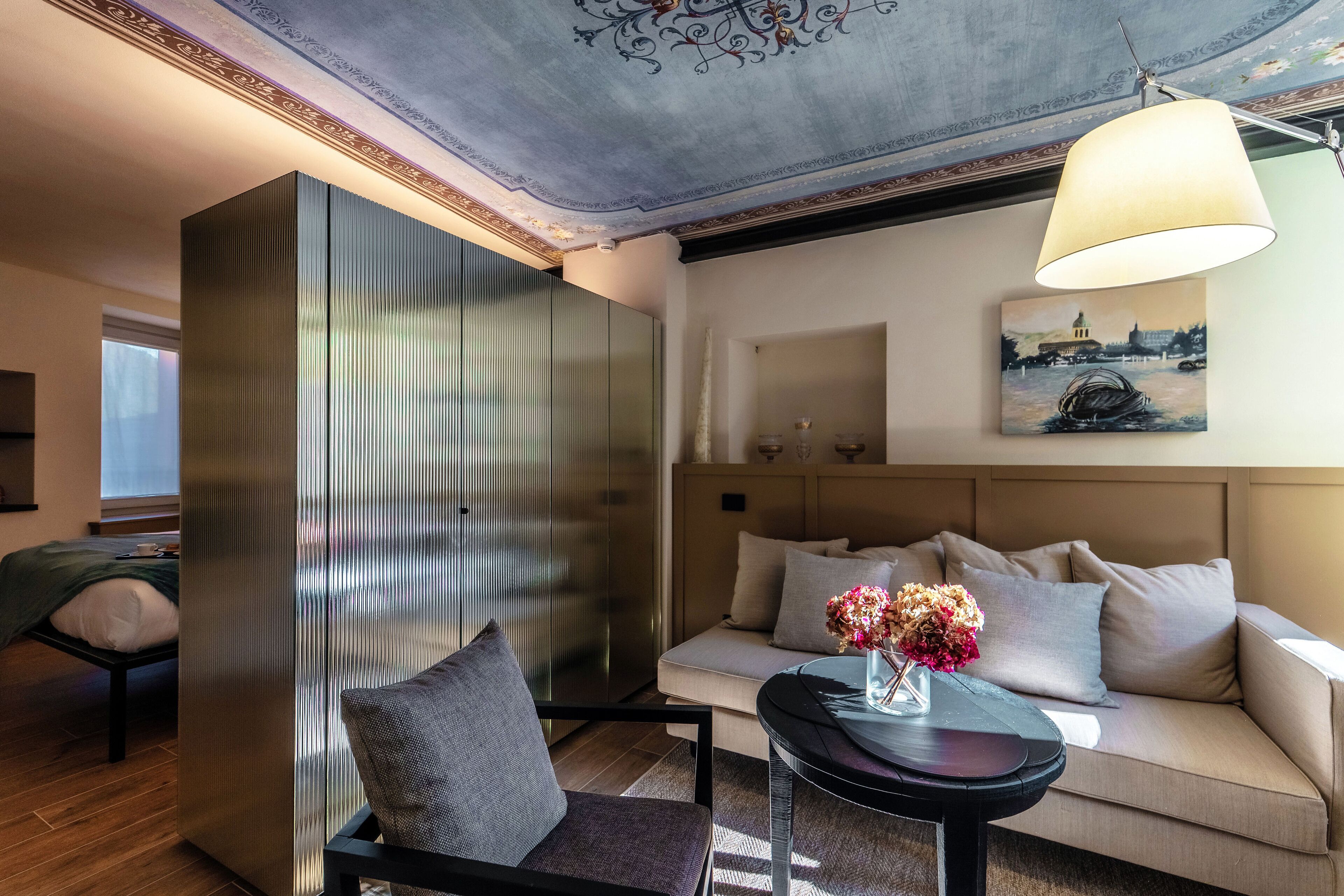 Una sala de estar moderna con un sofá, un sillón, una mesita con flores y un cuadro en la pared.