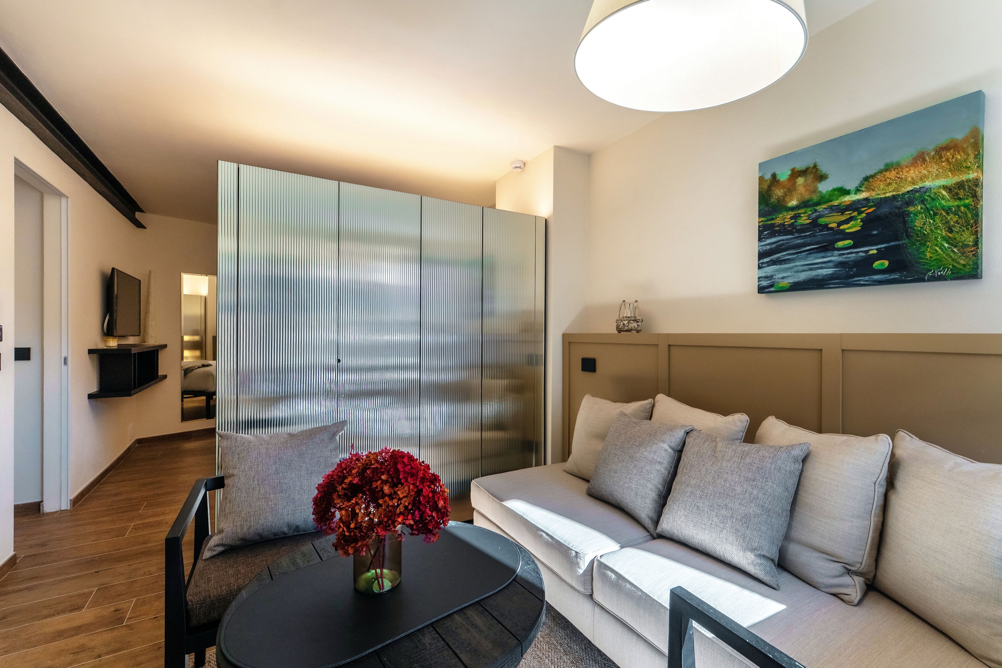 A modern living room with a sofa, a coffee table, and a painting on the wall.