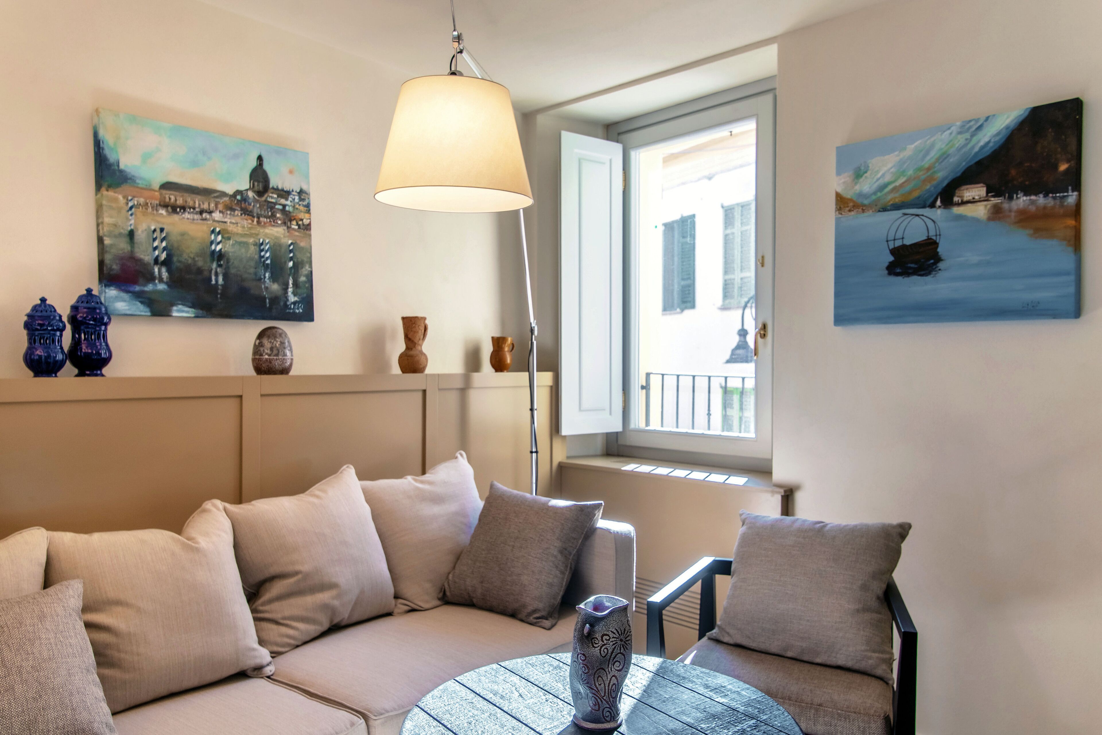 A cozy living room with a sofa, a round table, and two paintings on the wall.