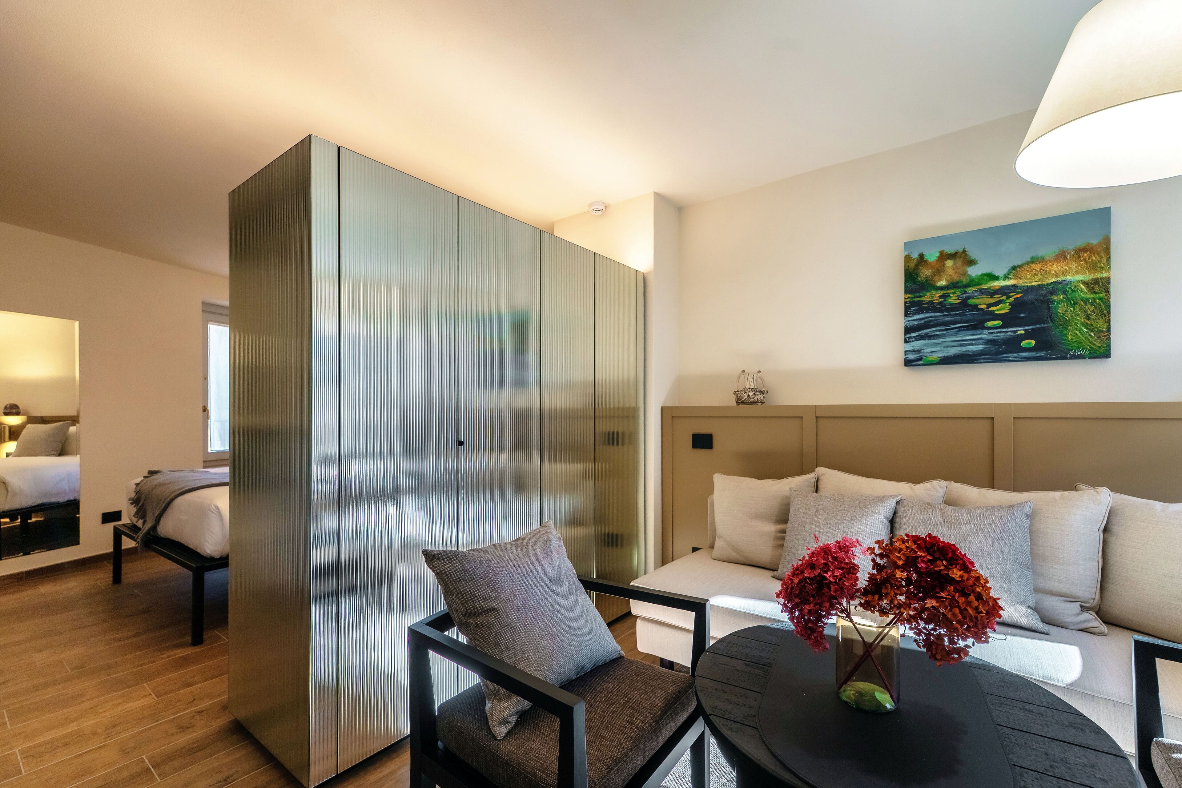 Een moderne hotelkamer met een bed, een bank, een eettafel en een schilderij aan de muur.