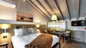 A bedroom with a large bed, bedside tables, a desk, and a chair. - Home Holidays (Argegno)