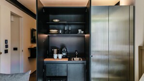 A compact kitchen with dark cabinetry, a coffee machine, and a small countertop. - Home Holidays (Argegno)