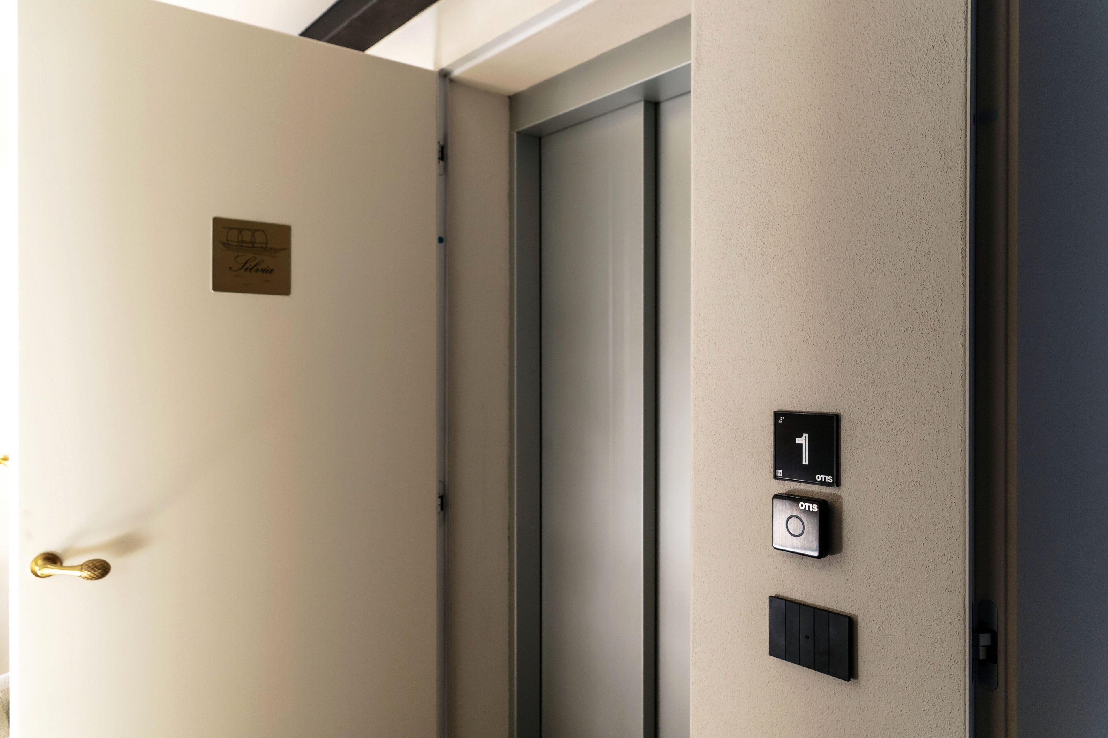 An elevator with a door, a control panel with a button, and a sign on the wall.