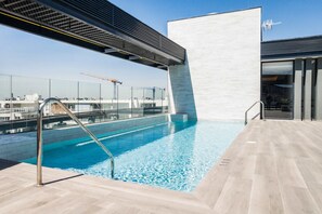 An indoor swimming pool with clear blue water, a modern architectural design, and a view of the cityscape in the background. - Sleek 1BR1BA Apt Urban Oasis for 3 in Las Condes (Las Condes)