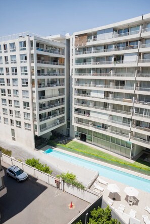 A multi-story residential building with balconies, a swimming pool, and outdoor seating. - Sleek 1BR1BA Apt Urban Oasis for 3 in Las Condes (Las Condes)