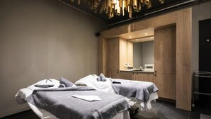 Un moderno cuarto de spa con dos camillas, un mueble de madera y un espejo.