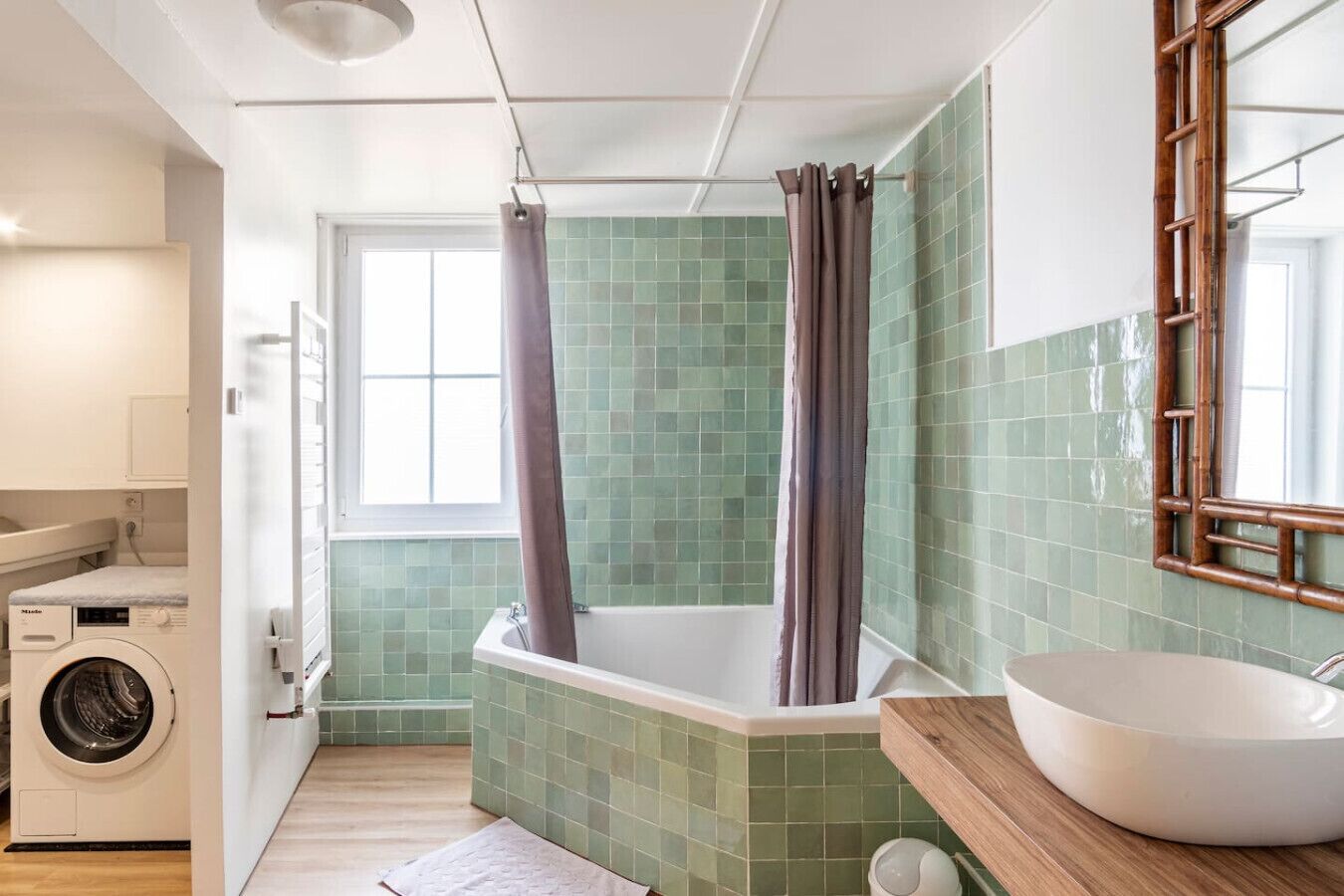 Een badkamer met een groen betegelde douche, een wit wastafelmeubel en een wasmachine.