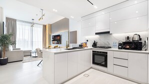 Een moderne keuken met witte kasten, een ingebouwde oven en een koffiezetapparaat.