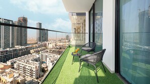 Een balkon met uitzicht op de stad, een klein tafeltje met drankjes en twee stoelen.