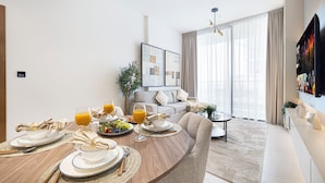 Een moderne woonkamer met een eethoek, met een bank, een salontafel en een aan de muur bevestigde televisie.