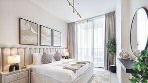 Een moderne slaapkamer met een groot bed, nachtkastjes, een spiegel en kunst aan de muur.