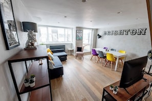 Un salon moderne comprenant un canapé, une table à manger et des chaises, une cheminée et un téléviseur.