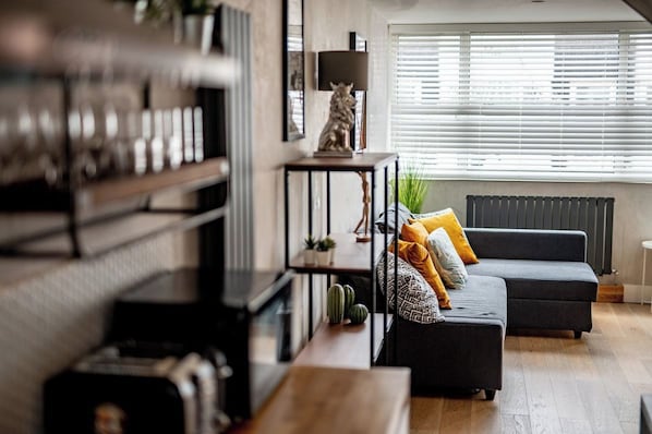 Un salon moderne avec un canapé d’angle, une table basse et une bibliothèque.