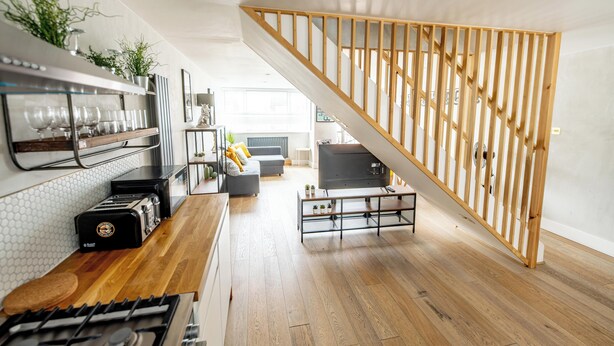 A modern kitchen with a wooden staircase, a dining area, and a living room with a TV. - Boutique-Style Apartment in The Heart of Brighton Centre (Brighton and Hove)