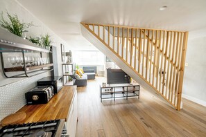 A modern kitchen with a wooden staircase, a dining area, and a living room with a TV. - Boutique-Style Apartment in The Heart of Brighton Centre (Brighton and Hove)