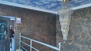 Un hall d’hôtel avec un mur de marbre, un lustre et un comptoir d’accueil.