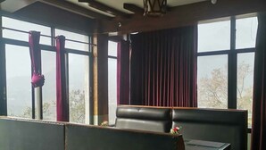 Un hall d’hôtel moderne doté d’un espace salon, de grandes fenêtres et d’un ventilateur de plafond.