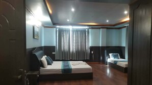 Une chambre d’hôtel avec un grand lit, un lit plus petit, un bureau et une armoire.