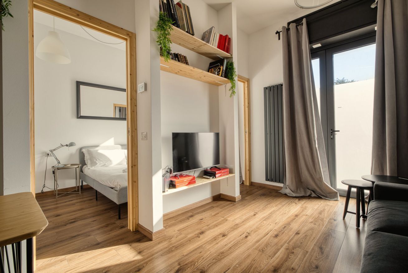 Ein modernes Wohnzimmer mit einem Bett, einem Fernseher, einem Bücherregal und einem Essbereich.