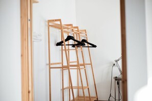 Een kamer met een houten garderobe, een bureau met een lamp en een kledingroede met kleding.