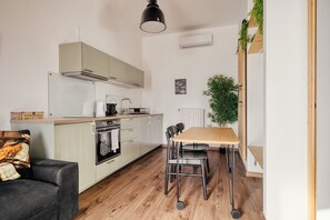 Een kleine keuken met een eethoek, houten vloeren en een zwart hanglamp.