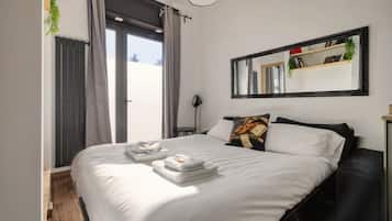 A bedroom with a bed, a mirror, and a window with curtains.