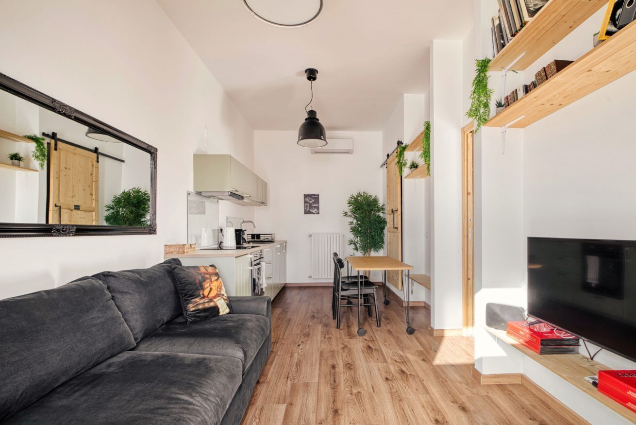 A modern living room with a sofa, a dining table, and a TV.