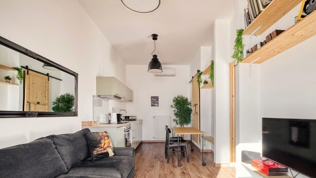 Una sala de estar moderna con un sofá, una mesa de comedor y un televisor.