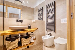 Ein modernes Badezimmer mit einem großen Spiegel, einem Holzwaschtisch, einem weißen Waschbecken und einem Bidet.
