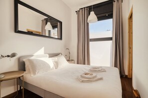Ein Hotelzimmer mit Bett, Schreibtisch, Spiegel und einem Fenster mit Vorhängen.