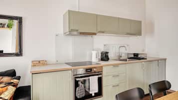 A compact kitchen with a built-in oven, a coffee maker, and a kettle on the countertop.