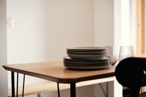 Een eettafel met gestapelde borden en een glas.