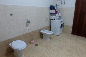 Un baño con inodoro, bidé y lavadora.