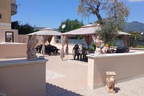 Un área de estar al aire libre con sombrillas, una estatua y una mesa con un jarrón de flores.