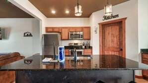 A modern kitchen with a central island, wooden cabinets, stainless steel appliances, and pendant lighting. - Luxe Cabin, Sleeps 11, Sauna, Gym, Theater Game (Sevierville)